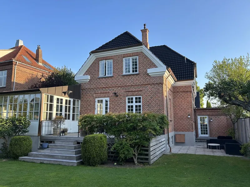 Rød murstensvilla med sort tag og have i Charlottenlund