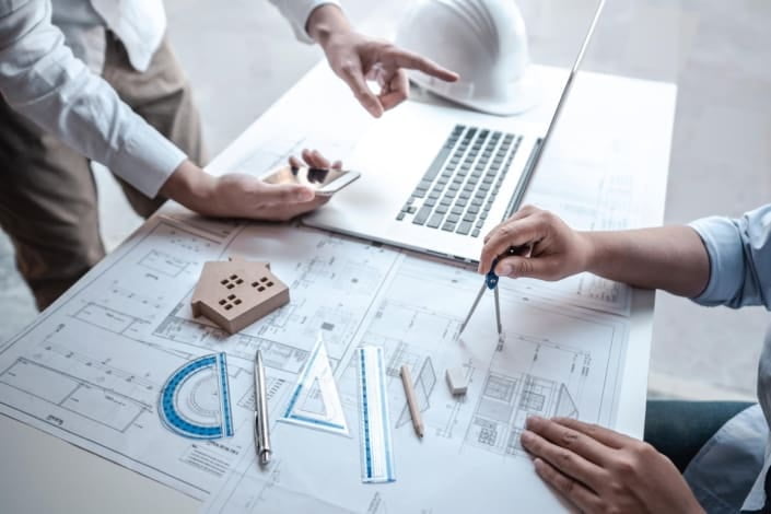 Arkitekter diskuterer byggetegninger på kontor