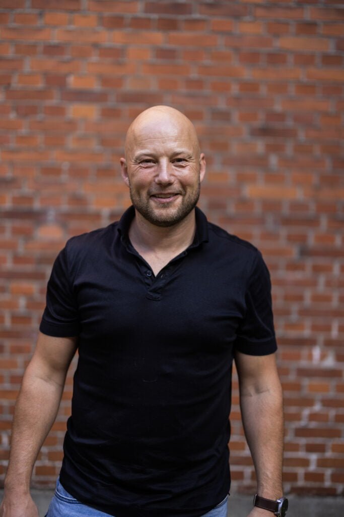 Mand smiler foran murstensvæg